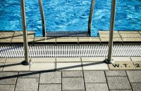 Close-up of a pool ladder with blue water, showcasing a serene outdoor setting.